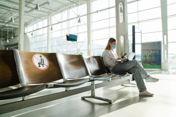 Female Traveler Mask Sitting Airport Lobby Chair Social Distancing Sign — Stockfoto