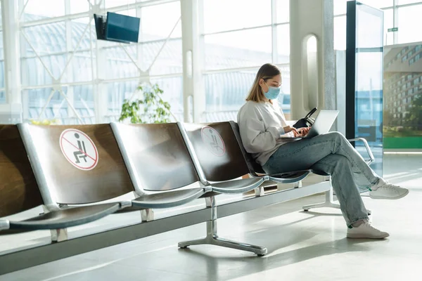 Female Traveler Mask Sitting Airport Lobby Chair Social Distancing Sign — Stockfoto