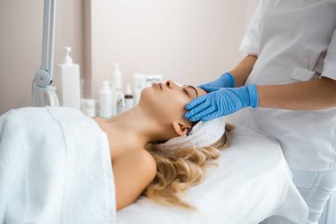 Beautician massaging the face of young girl in latex gloves. Masseur doing relax facial massage at spa salon