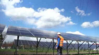Solar power plant worker in uniform fixing panels with a drill. Engineer near solar panels