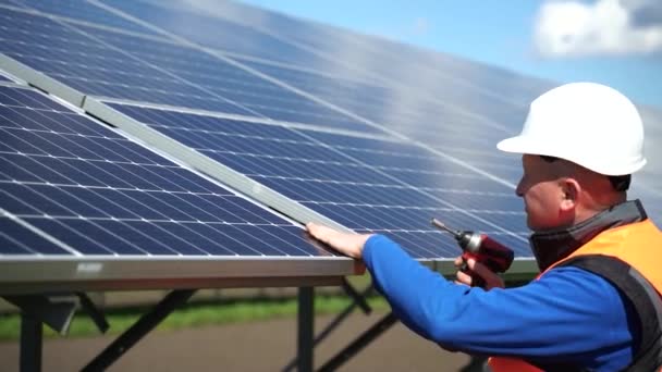 ドリルを使用してボルトで金属ベースにパネルを固定太陽光発電所のエンジニア ソーラーパネルを修理する電動レンチを持つ男 — ストック動画