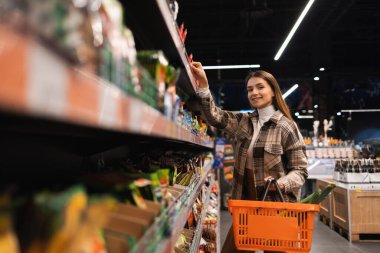 Süpermarkette alışveriş sepeti ile genç kadın