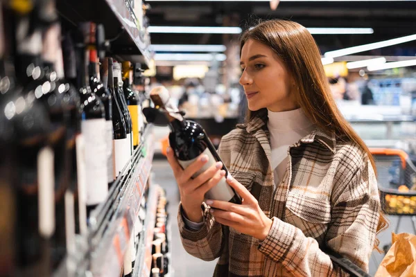 Woman choosing wine in supermarket