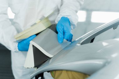 Otomobil tamiri ve yenilenen servis istasyonunda boya örnekleriyle otomobil boyacısı renk seçiyor