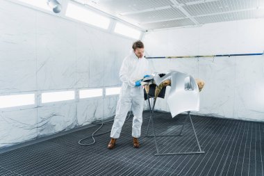 Araba tamponu için renk seçen bir boyacı. Otomobil boyama standında çalışan bir adam.