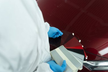 Araba boyacısı renk örnekleri arasında ihtiyacı olan boyayı arıyor.