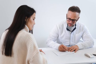 Erkek doktor hastası için reçete yazıyor.