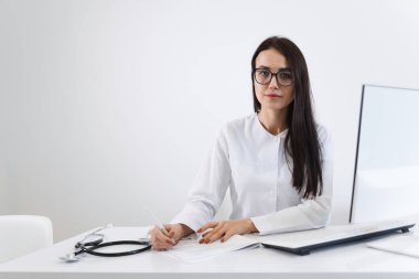 Ofisteki iş yerinde otururken genç kadın doktorun portresi dolduruyor.