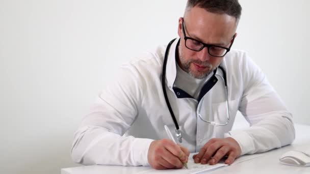 男性医師が処方箋を書いている 事務所で働く医師の肖像画 — ストック動画