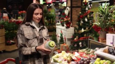 Süpermarketin meyve reyonundaki güzel genç kadın papayayı seçiyor..