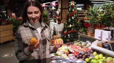 Süpermarkette egzotik kiwano meyvesi seçen neşeli bir kadın. Marketin meyve reyonundaki kız..
