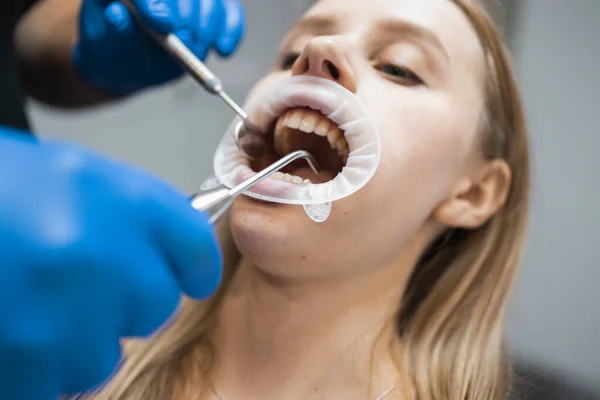 Dentist rinses the oral cavity of the patient on the dentist\'s chair. Doctor treats a patients teeth in a stamotology clinic
