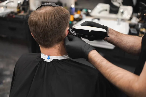 プロの男性の美容師は理髪店で男にヘアスタイルを行います 床屋の主人が男を切り刻む — ストック写真