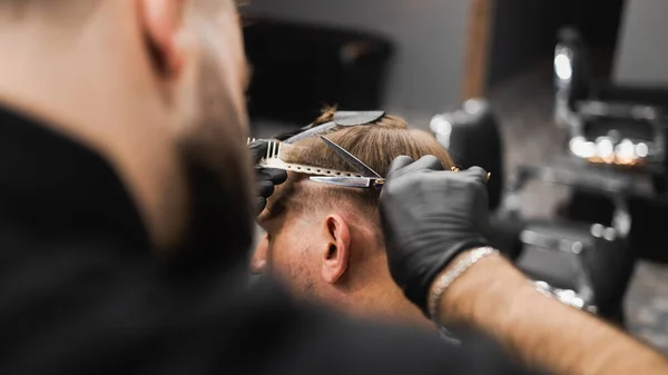 理髪店でスタイリッシュな黒髪の男のための頭側の美容師はさみ髪 — ストック写真