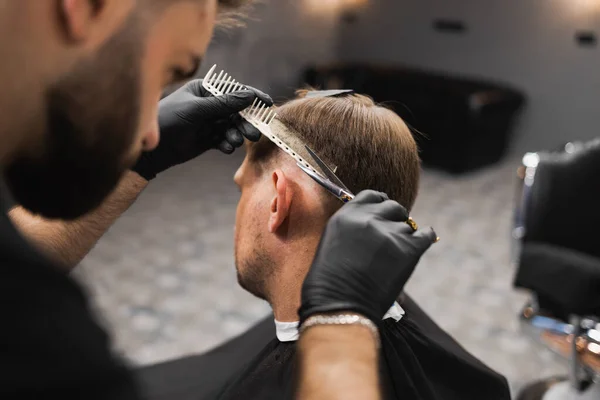 理髪店でスタイリッシュな黒髪の男のための頭側の美容師はさみ髪 — ストック写真