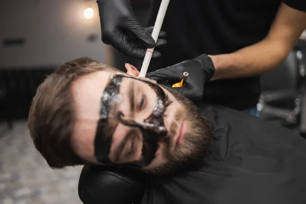 美容室の男はろうそくを使って耳垢を除去しています 温泉療法を楽しむ男性 — ストック写真