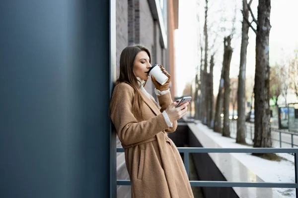 Vista Lateral Una Mujer Joven Abrigo Marrón Bebiendo Café Caliente — Foto de Stock