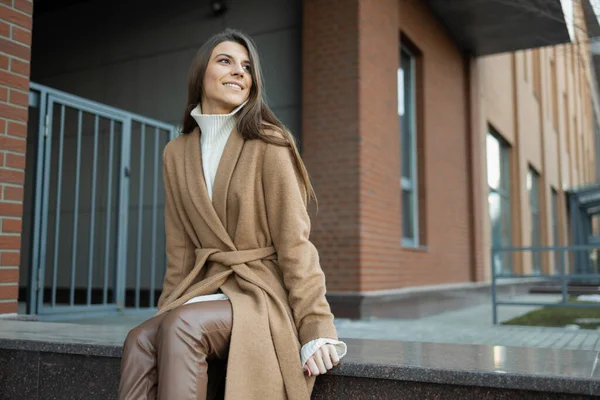 茶色いコートを着た美しい女性が通りの真ん中に座っている — ストック写真