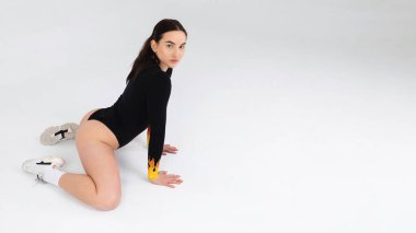 Siyah elbiseli ve spor ayakkabılı seksi kız stüdyoda seks dansı yapıyor.