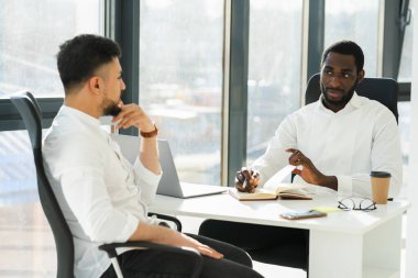 Siyahi adam şirket ofisindeki yeni çalışanla röportaj yapıyor.