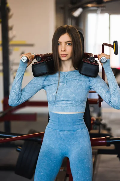 Spor salonundaki antrenman makinesine çömelmiş bir kız.