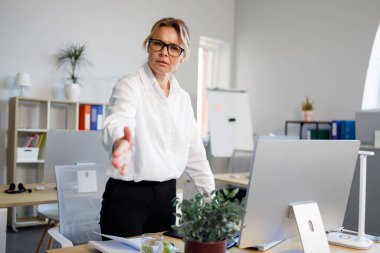 Olgun bir ofis çalışanı elini sıkar. Selamlar, iyi bir anlaşma işareti.