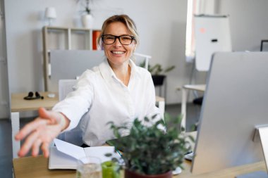 Dost canlısı iş kadını el sıkışmak için el sıkışıyor. Bayan danışman, müşteriyi ofiste karşılıyor.