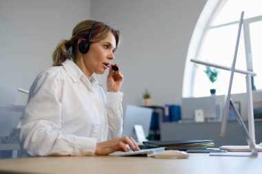 Ofiste bilgisayarla çalışan güzel bir kadın çağrı merkezi operatörü. Yardım hattı çalışanı 