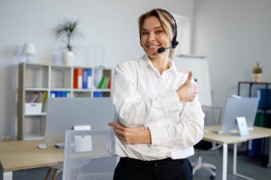 Mutlu kadın çağrı merkezi operatörü başparmaklarını gösteriyor.