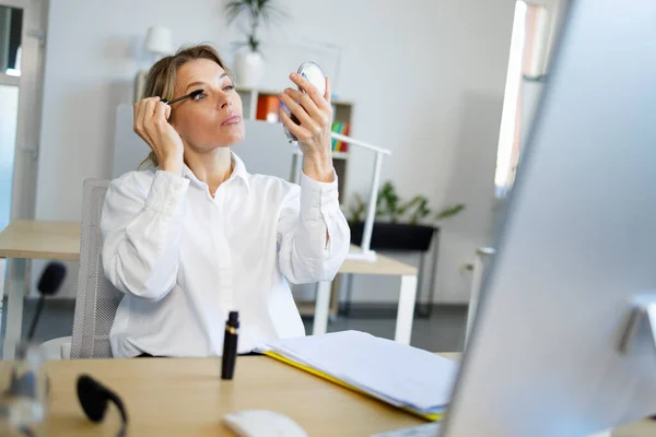 Elegant Business Woman Refreshes Makeup Applying Mascara While Sitting Workplace — Zdjęcie stockowe