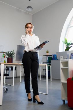 şık iş kadını ofiste telefonda konuşuyor