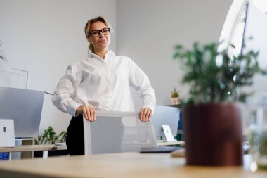 Ofiste duran güzel, olgun bir iş kadını portresi.