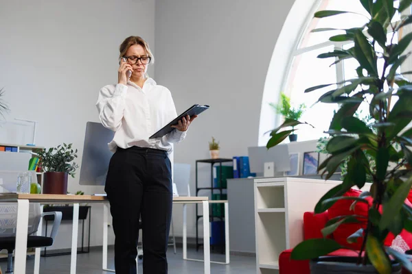 Memnuniyetsiz ofis çalışanı telefonda konuşuyor.