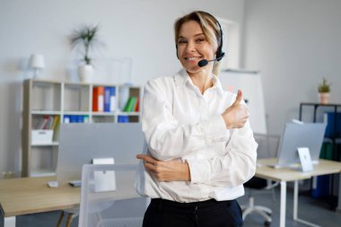 Mutlu kadın çağrı merkezi operatörü başparmaklarını gösteriyor.