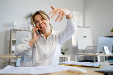 Meşgul bir iş kadını telefonda konuşuyor ve çalışanından ofisten çıkmasını istiyor.