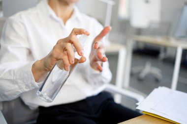 İş kadını bir ofis çalışanının ellerine antiseptik sıkarken yakın plan görüntüsü.