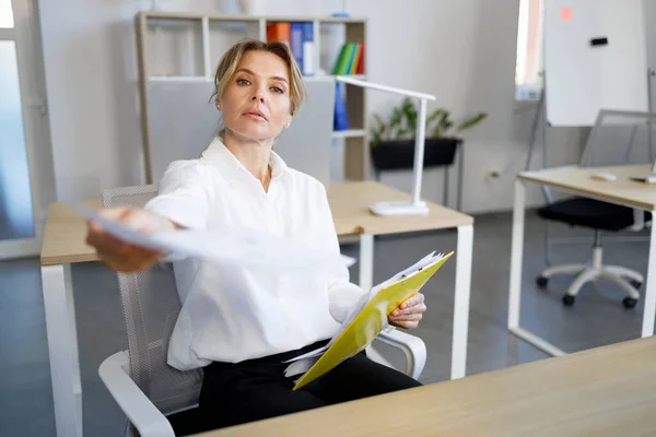 Strict Businesswoman Sitting Desk Giving Document Someone — Zdjęcie stockowe