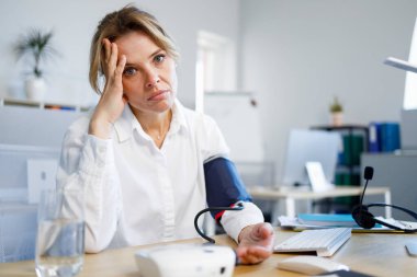 Portrait of unwell business woman who measures blood pressure