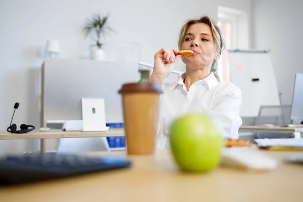 Business Woman Eating Cookies While Sitting Her Desk —  Fotos de Stock