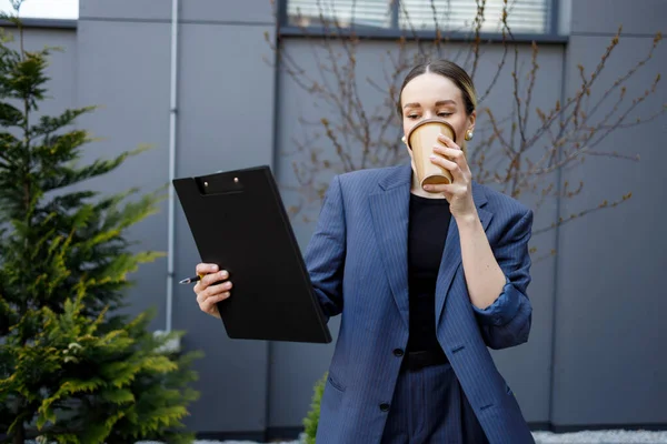 クリップボードコーヒーを屋外で飲むビジネス女性 — ストック写真