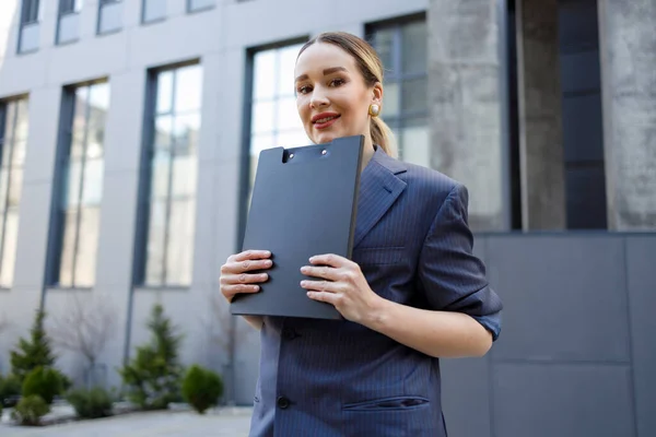 Business woman in formal wear with a folder in hands