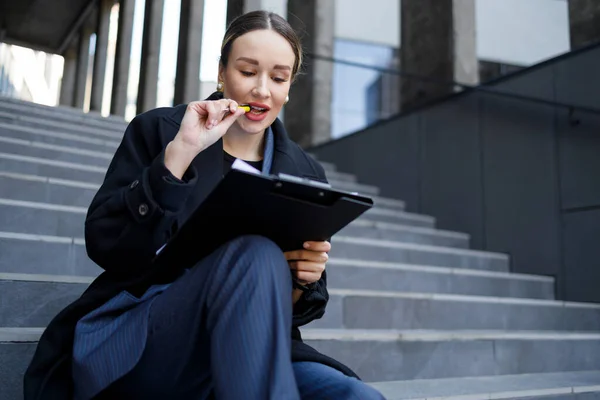 クリップボード付きの階段に座っているビジネス女性 — ストック写真