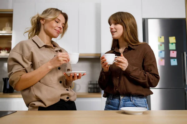 母と娘はキッチンでコーヒーや紅茶を話して飲みます — ストック写真