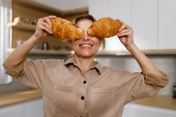 大人の女性はクロワッサンで目を覆いました 焼きたてのクロワッサンを食欲をそそる主婦 — ストック写真