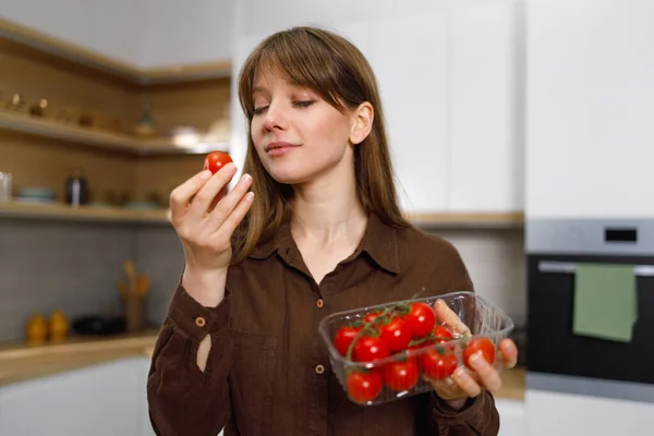 Jonge Veganistische Vrouw Onderzoekt Kerstomaten Terwijl Keuken Staat — Stockfoto