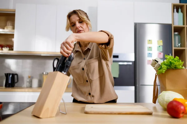 Volwassen Vrouw Keuken Neemt Mes Uit Blok Huisvrouw Maakt Zich — Stockfoto