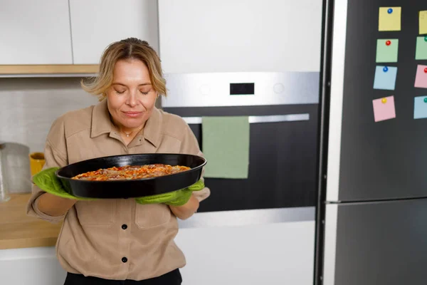 Woman Takes Freshly Baked Pizza Out Oven Sniffs — Stock Photo, Image