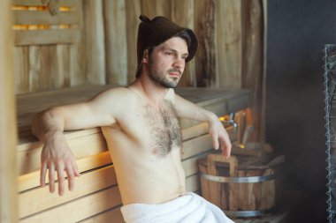 Sauna banyosu yapan ciddi bir adam.