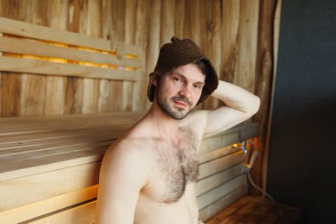 Saunada dinlenen çekici bir adam.