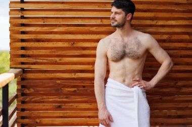 Havluyla kaplıca otelinin terasında poz veren başarılı bir adam.